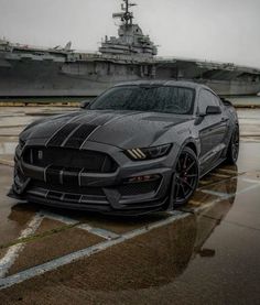 a gray car parked in front of a large aircraft carrier