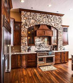 a kitchen with wood flooring and stone wall