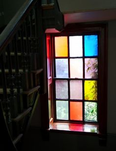 an open window with multicolored glass on the outside and stairs in the background