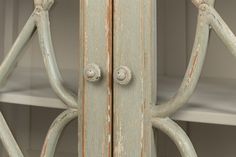 an old wooden cabinet with two doors and knobs on the front, behind which is a shelf