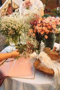 a table topped with vases filled with flowers next to a person sitting at a table