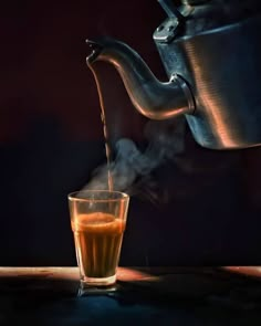 a glass filled with liquid next to a tea kettle