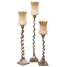 three metal candlesticks sitting next to each other on a white background with one candle in the middle