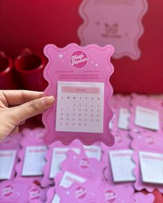 a person holding up a pink calendar card