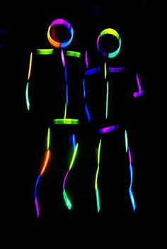 three people are standing in the dark with neon lights on their body and arms,