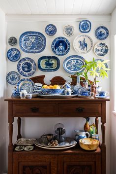 blue and white plates are on the wall above a wooden table with a potted plant