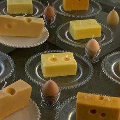 several different types of cheese on plates with candles in the shape of eggs and cheese slices