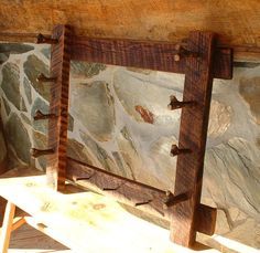 a wooden bench sitting in front of a stone wall with metal brackets on the back