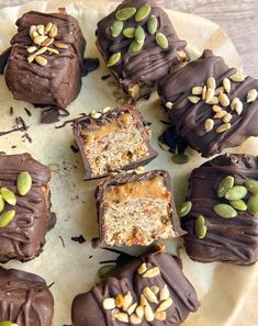 chocolate covered desserts with nuts and seeds on a white plate, ready to be eaten