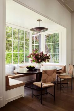 a dining room table with four chairs and a vase filled with flowers on top of it