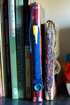 some books are sitting on a shelf with crocheted items in front of them