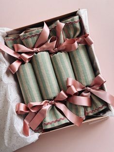 a box filled with pink ribbon wrapped in green and white striped paper next to a polka dot pillow