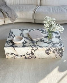 a marbled coffee table with a book and vase on it