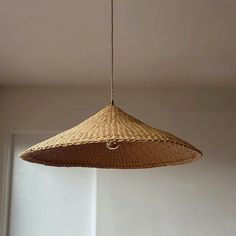 a large woven light fixture hanging from a ceiling in a room with white walls and flooring