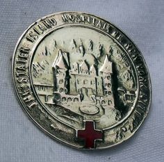 an old silver medal with a red cross on it's center and castle in the background