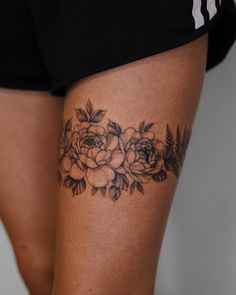 a close up of a person's thigh with flowers tattooed on the leg and behind her