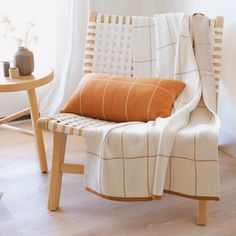 a white chair with an orange pillow on it