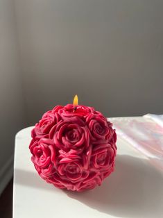 a candle that is sitting on top of a white table with pink flowers in it