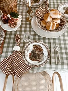 a table set for thanksgiving dinner with turkey plates and silverware