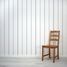 a wooden chair sitting in front of a white wall