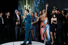 a man standing in front of a group of people holding up their awards on stage