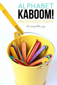 the alphabet kaboom preschool game is in a yellow bucket filled with colorful crayons