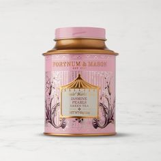 a pink jar with gold lid sitting on top of a white table