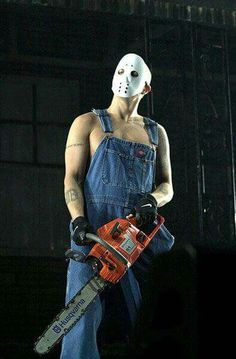 a man in overalls with a chainsaw on his face and wearing a mask