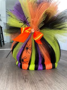 an orange, black and green halloween decoration on a wooden floor with spider webs