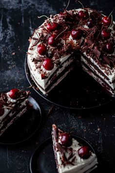 a chocolate cake with cherries on top and two slices missing from the cake plate