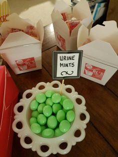 a bowl filled with green candies sitting on top of a table next to boxes