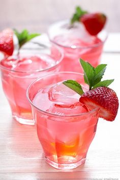 three glasses filled with pink lemonade and strawberries