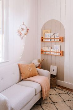 a living room with a white couch and bookshelves on the wall next to a window