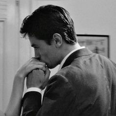 black and white photograph of a man in suit looking at something on the wall behind him