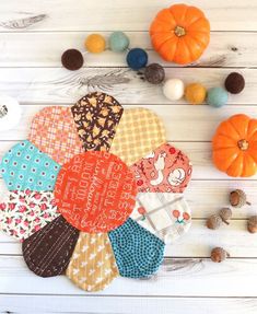 several pieces of fabric sitting on top of a white wooden table next to pumpkins