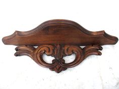 a wooden wall mounted shelf with an ornate design on the top and bottom half of it