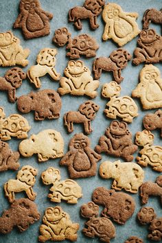 many different kinds of cookies are arranged on a blue tablecloth with white and brown icing