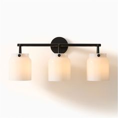 three light bathroom fixture with white glass shades and black metal bar arm, against a white wall