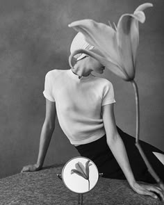 a woman sitting on top of a table next to a flower