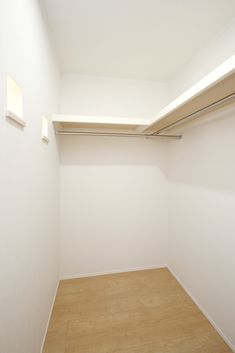 an empty closet with white walls and wooden floors