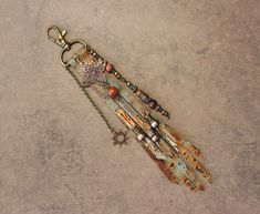 a key chain with beads and charms hanging from it's side on a concrete surface