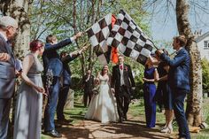 a group of people standing around each other holding up a checkered flag in the air