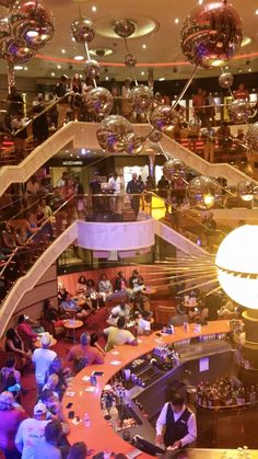 a large group of people sitting at tables in a room with disco balls hanging from the ceiling