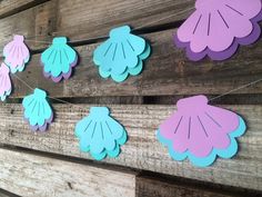 paper flowers are hanging on the side of a wooden wall with string attached to it