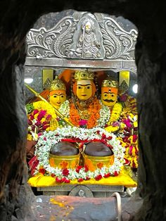 there is a statue in the middle of a cave with other statues behind it and flowers on the ground