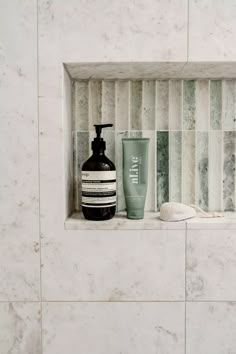 a bathroom shelf with soap, shampoo and lotion on it next to a tiled wall