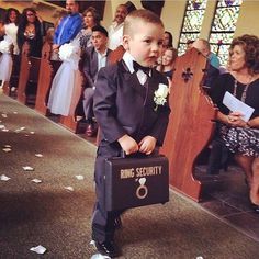 a young boy in a suit and tie holding a briefcase while people watch from the pews