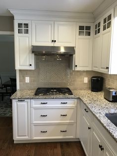 a kitchen with white cabinets and granite counter tops, along with a black stove top oven