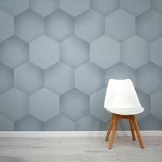 a white chair sitting in front of a wall with hexagonal tiles on it