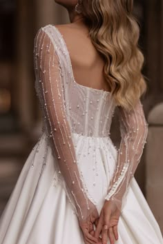 the back of a woman's wedding dress with long sleeves and beaded detailing